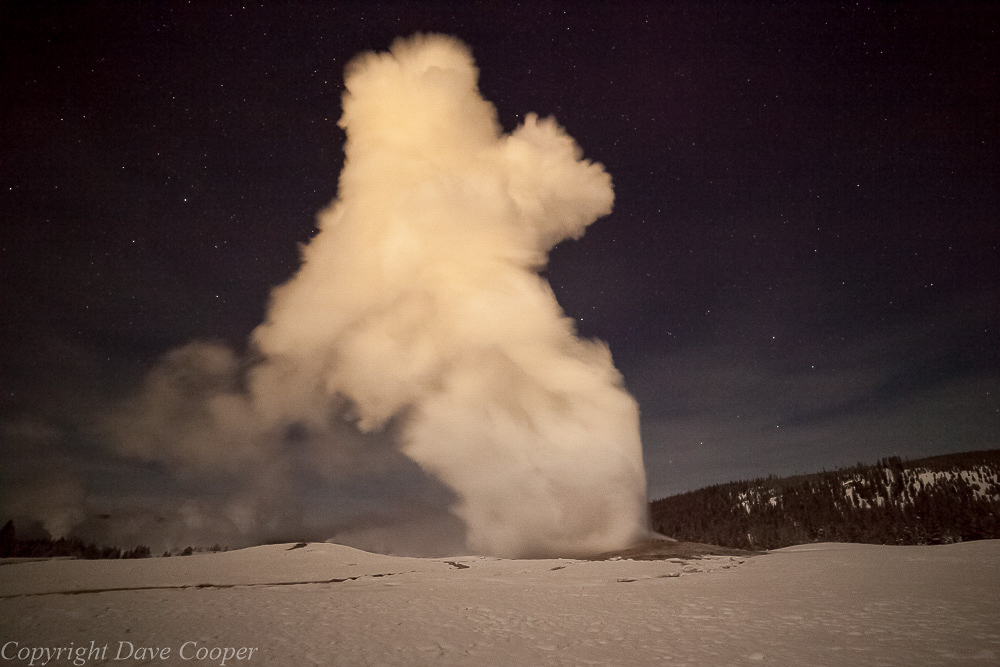 Night-time photo of Old Faithful with stars